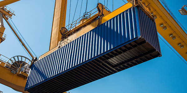 Shipping container being moved by crane